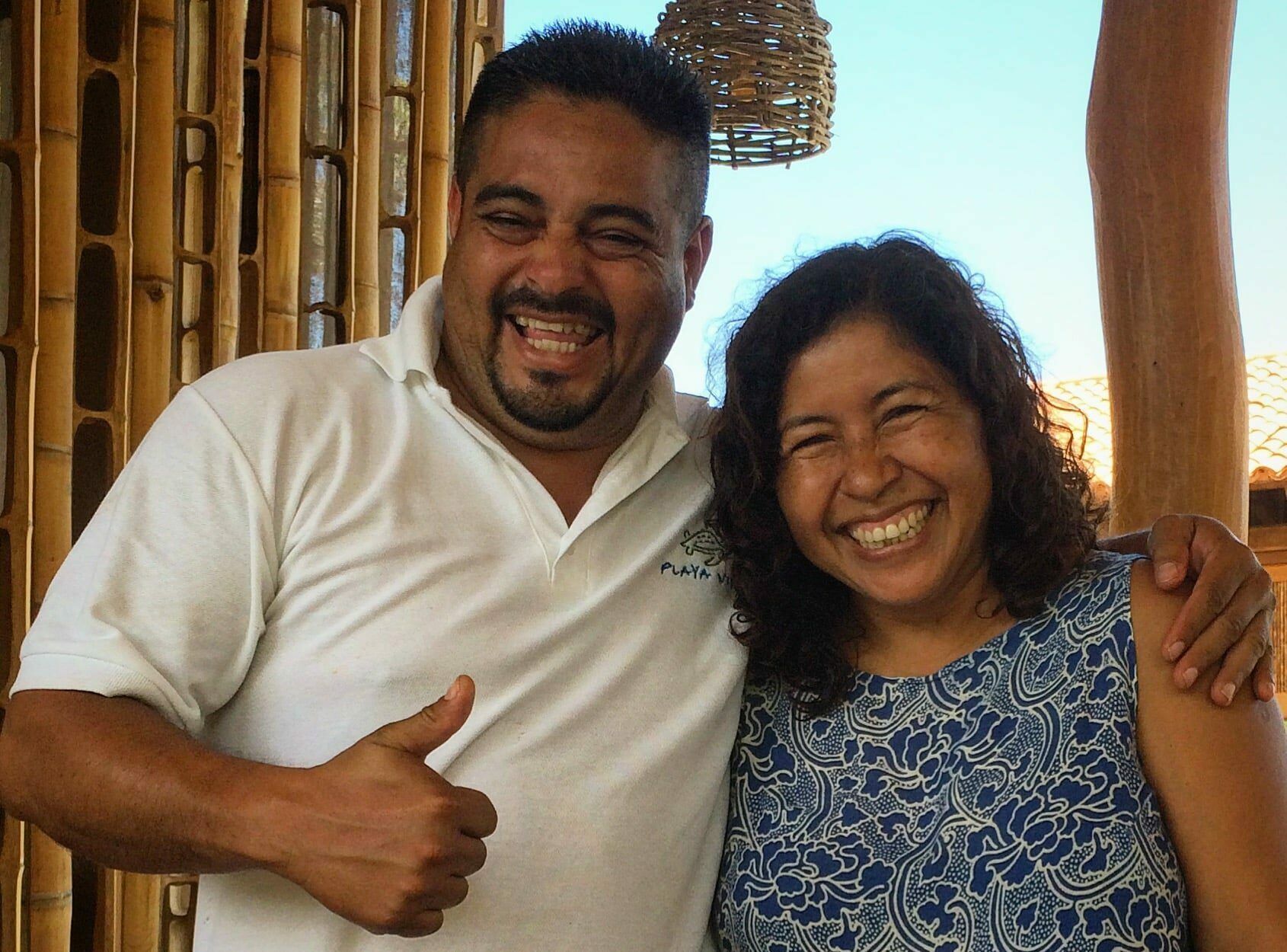 A man and a woman are posing for a picture and the man is giving a thumbs up