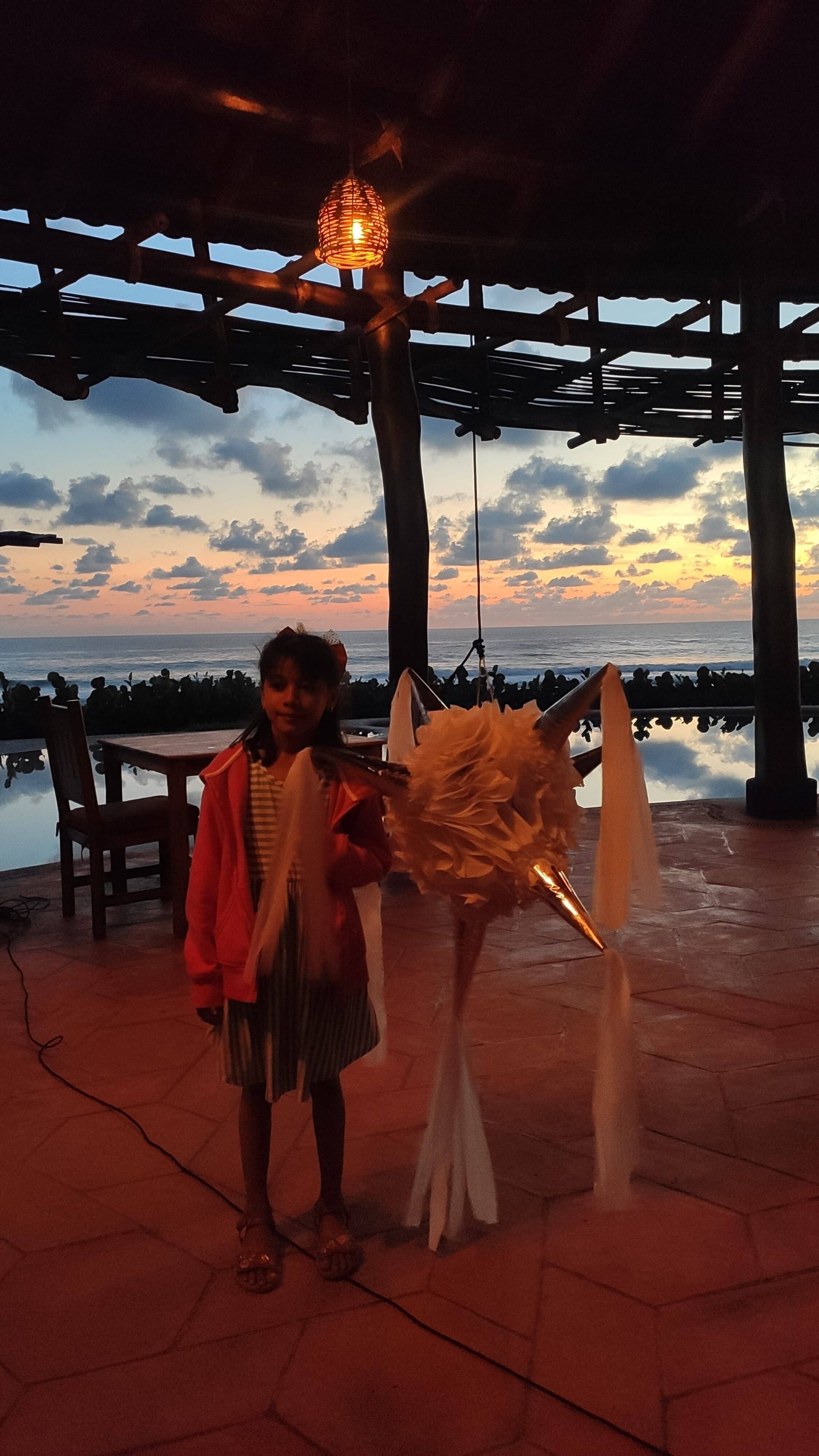 A little girl is standing next to a statue of a dragon.