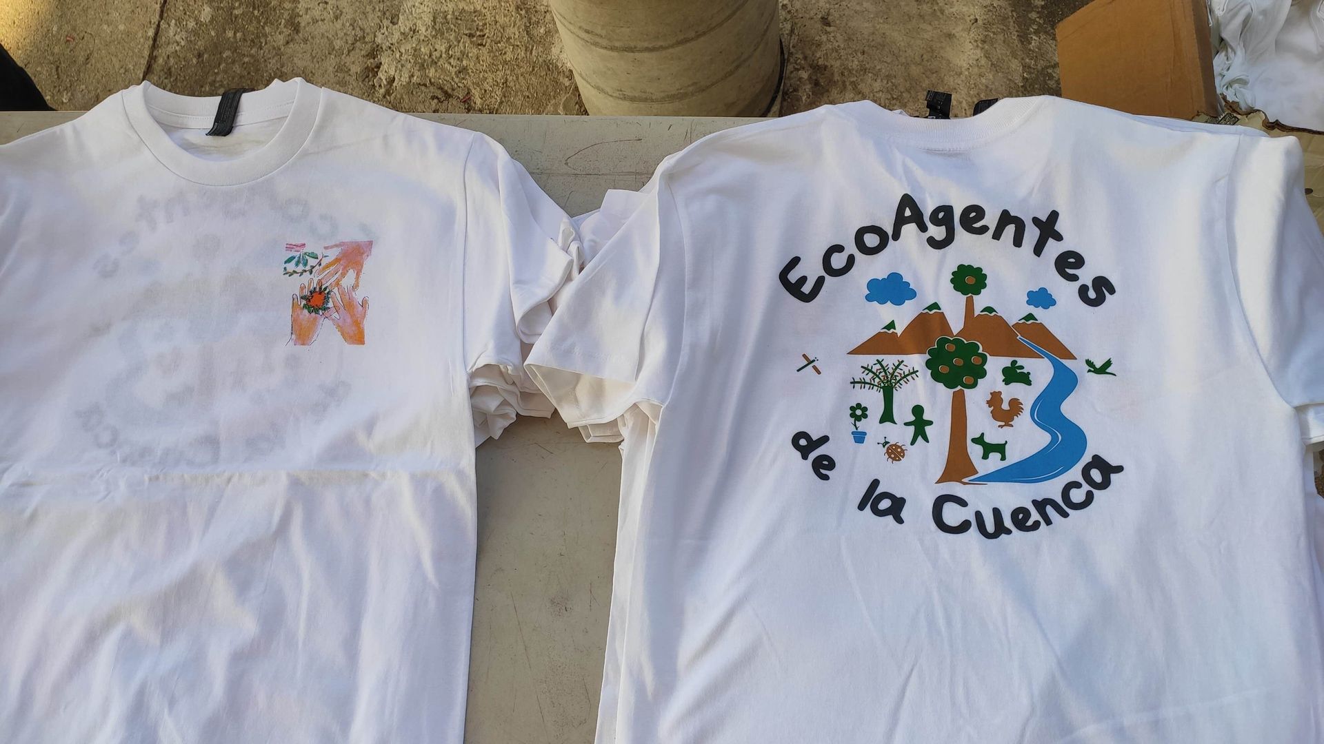 Two white t-shirts with the words ecoagentes de la cuenca on them