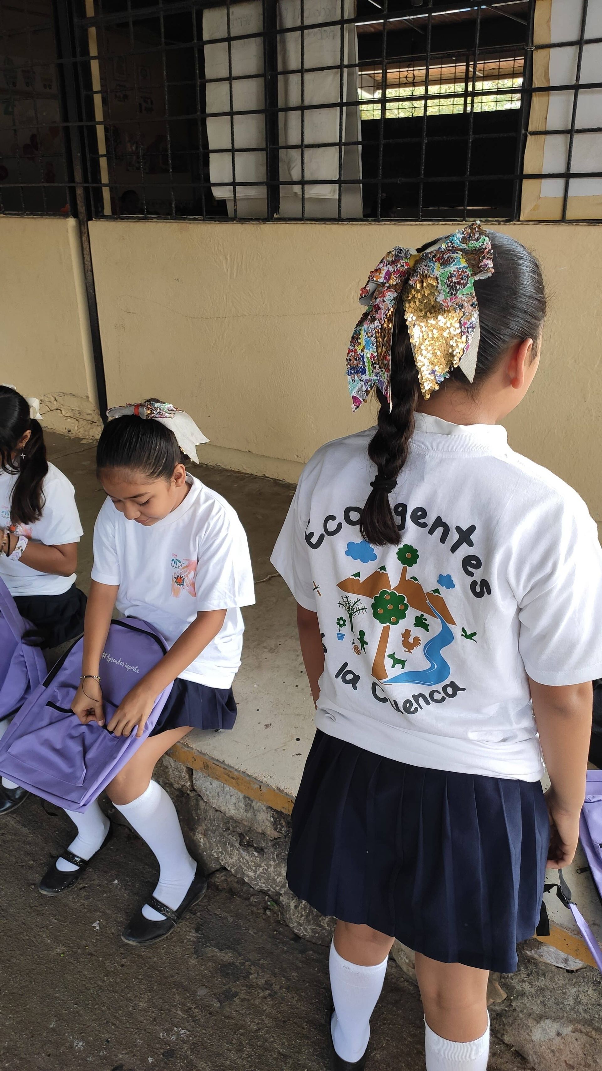 A girl in a school uniform is standing in front of a building.
