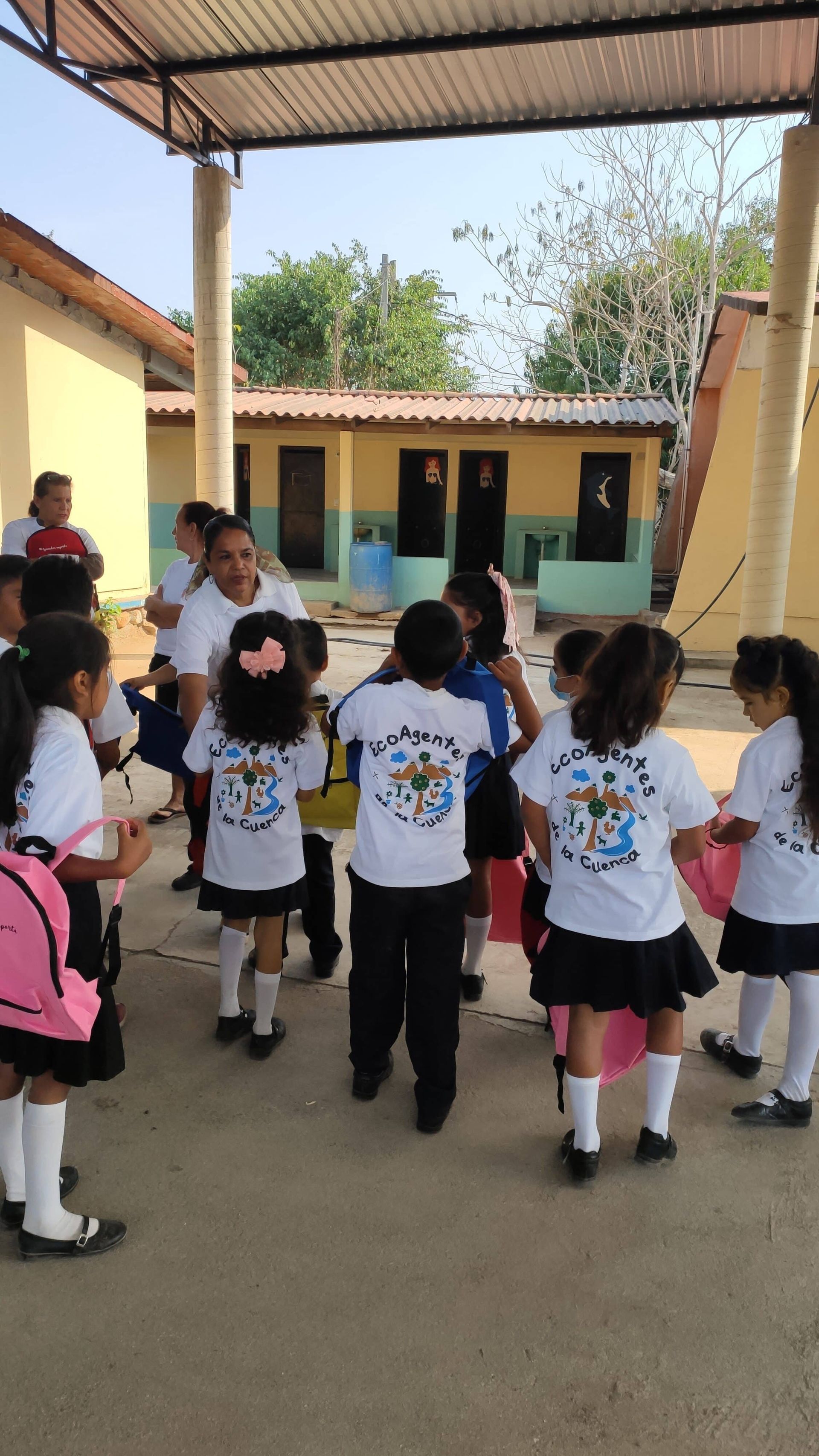 A group of children in school uniforms are standing in front of a building