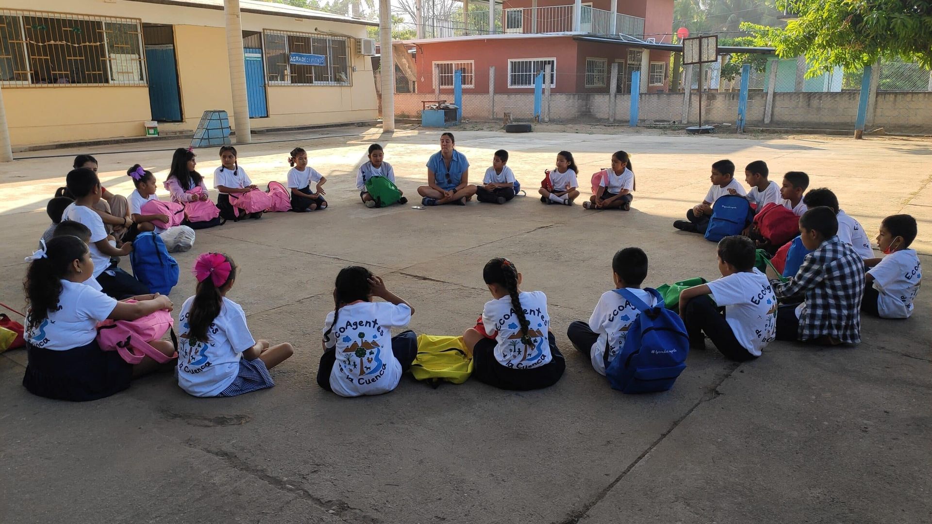 A group of children are sitting in a circle on the ground.