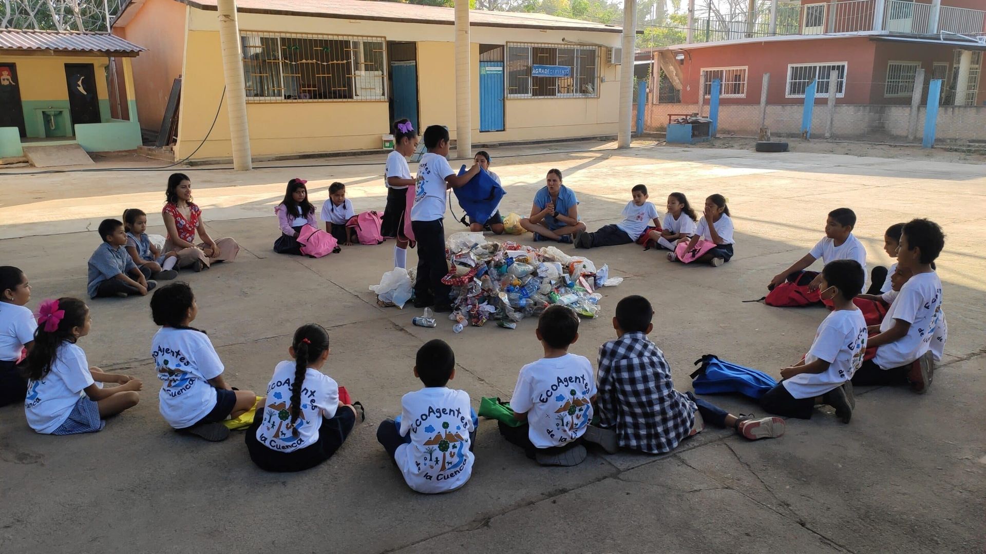 A group of children are sitting in a circle on the ground