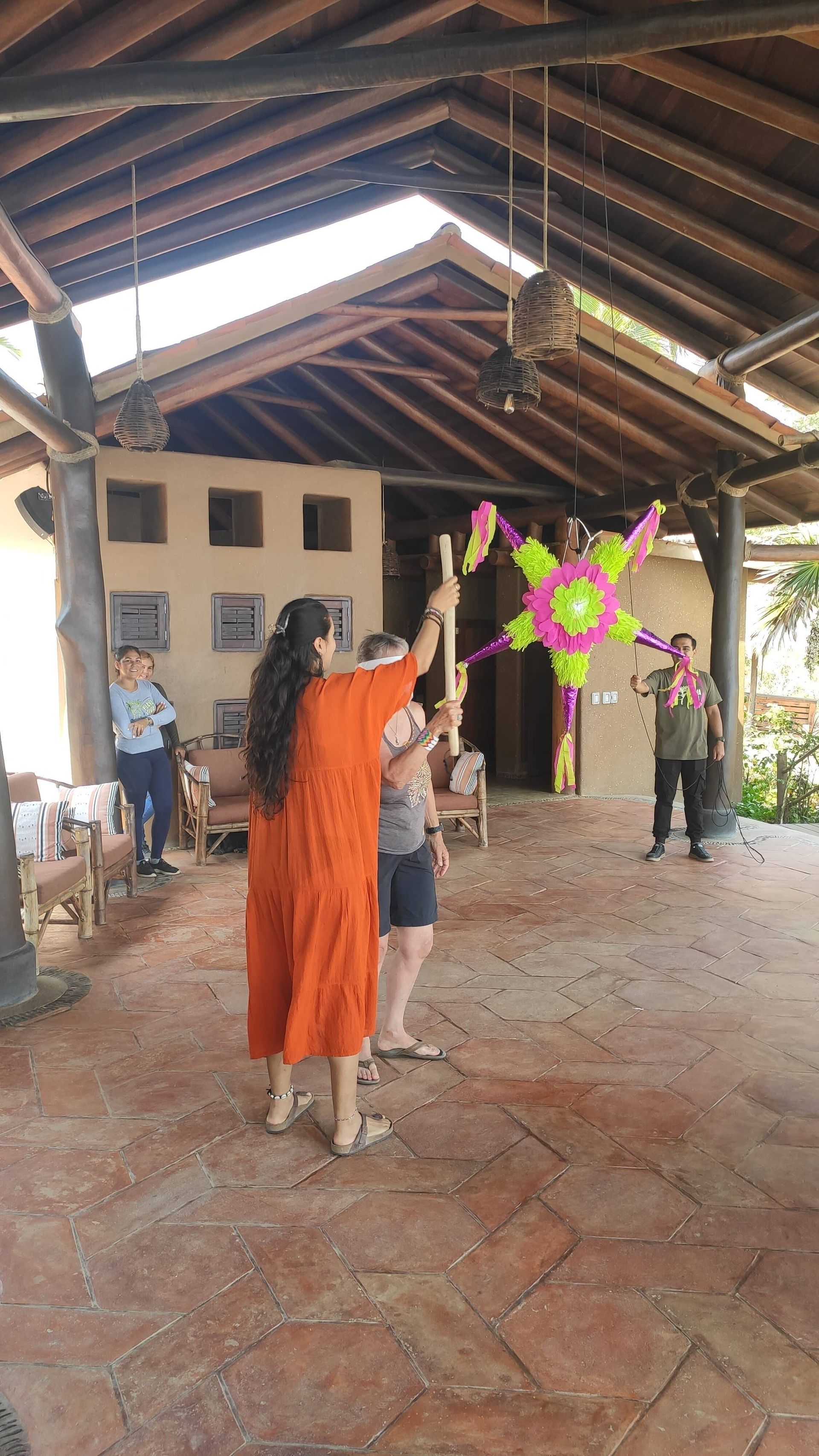 A woman and a child are playing with a pinata in a room.