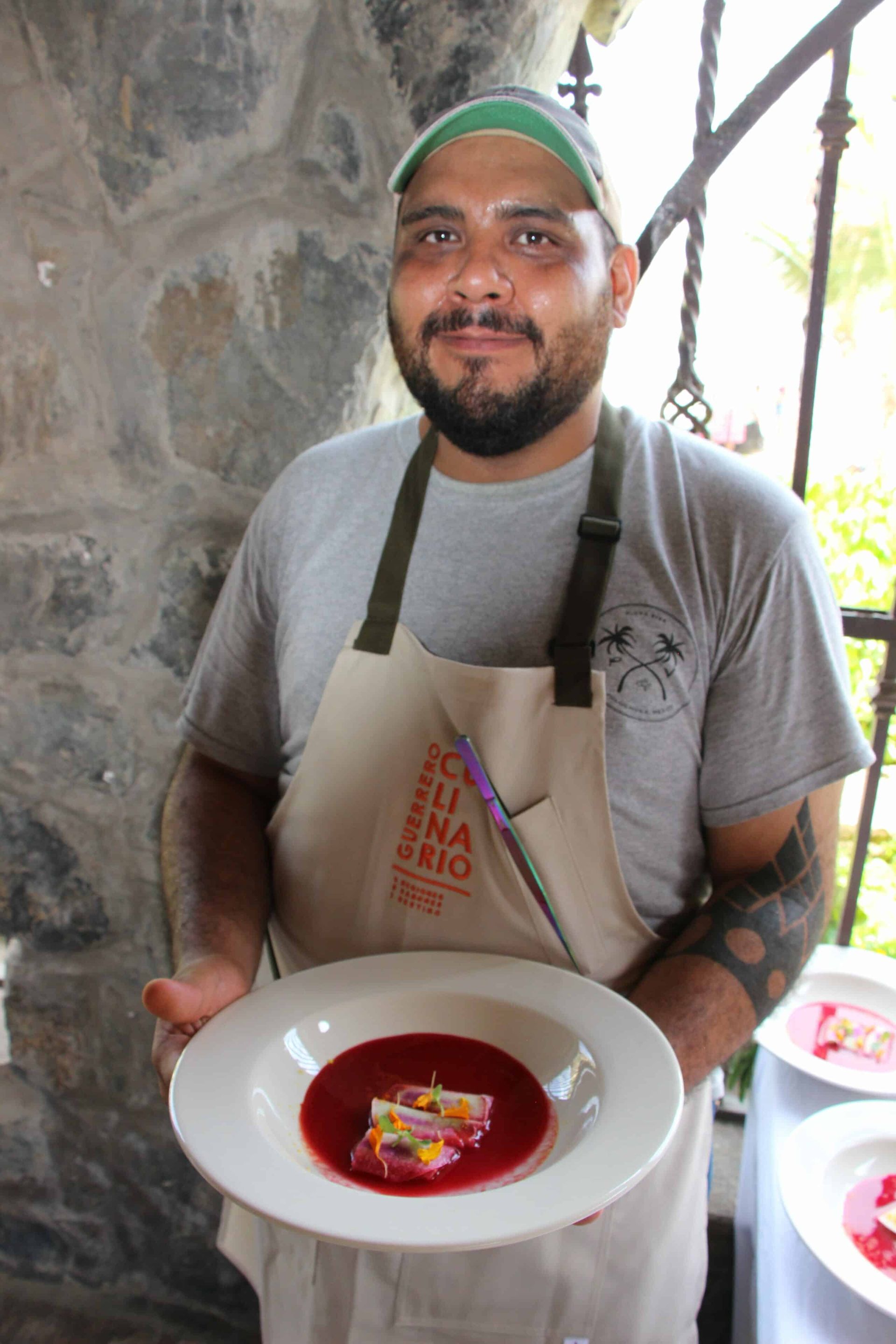 A man in an apron is holding a plate of food