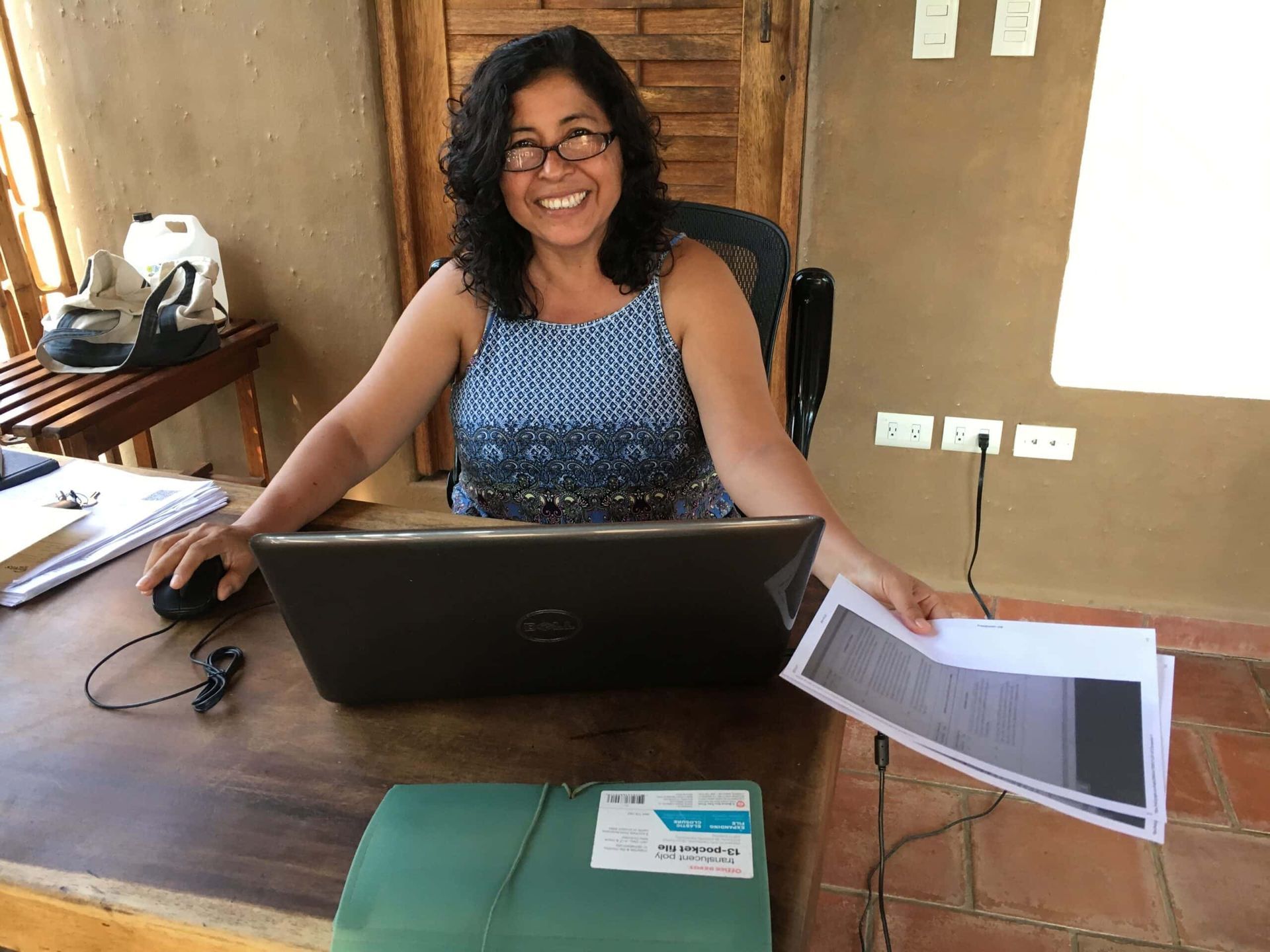 A woman is sitting at a desk using a dell laptop