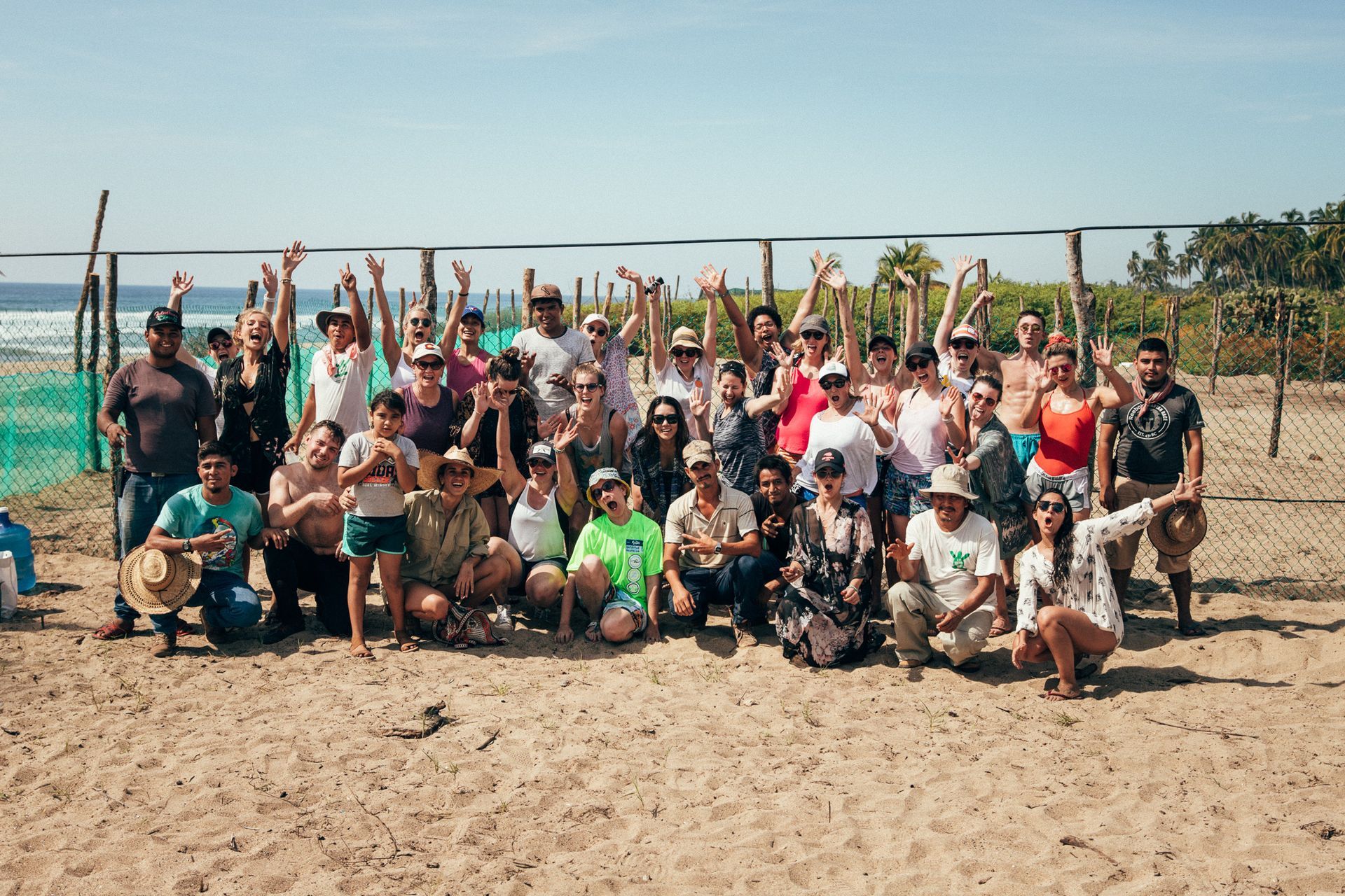 A large group of people are posing for a picture on a beach.