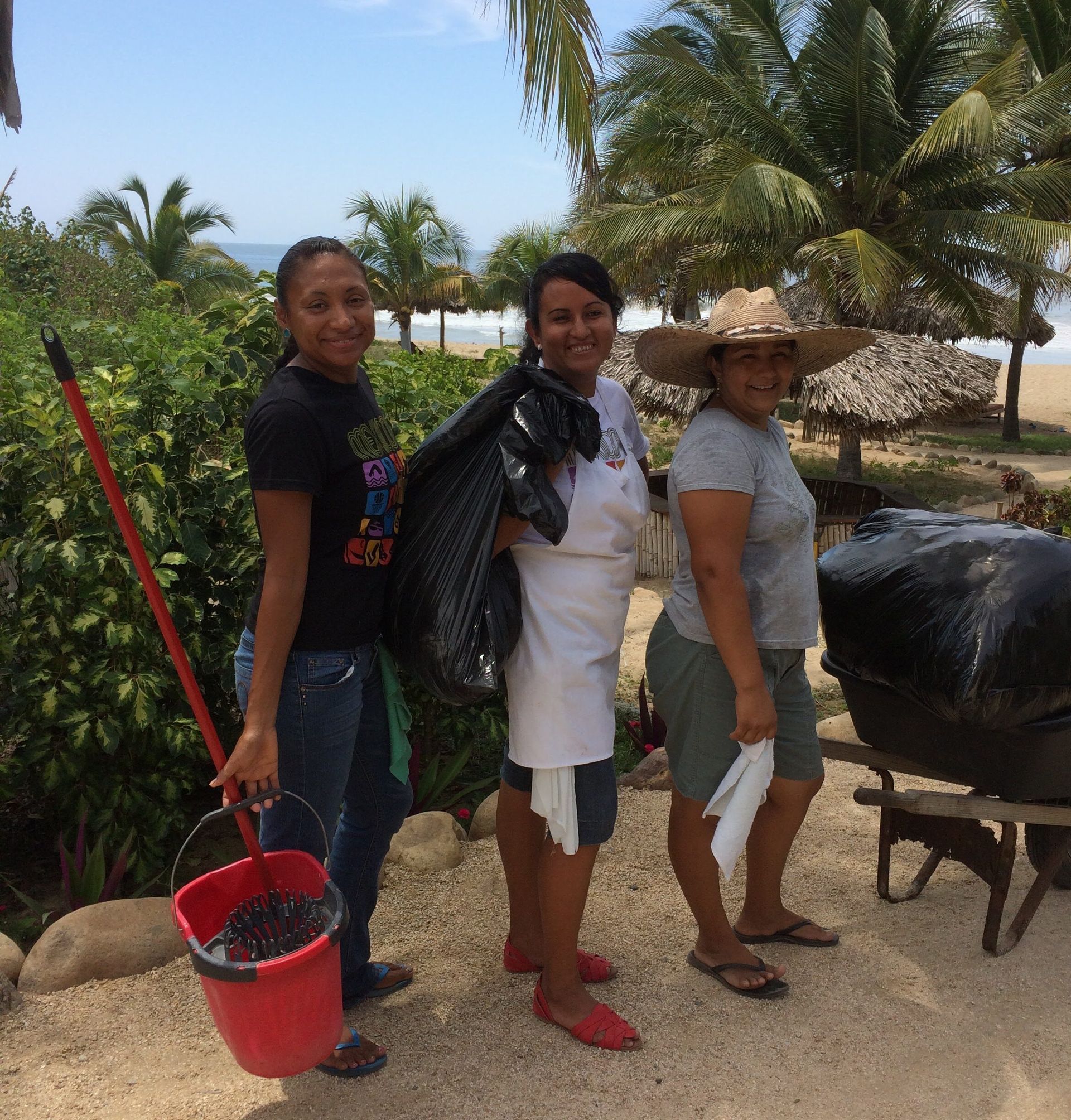Three women standing next to each other with one holding a red bucket