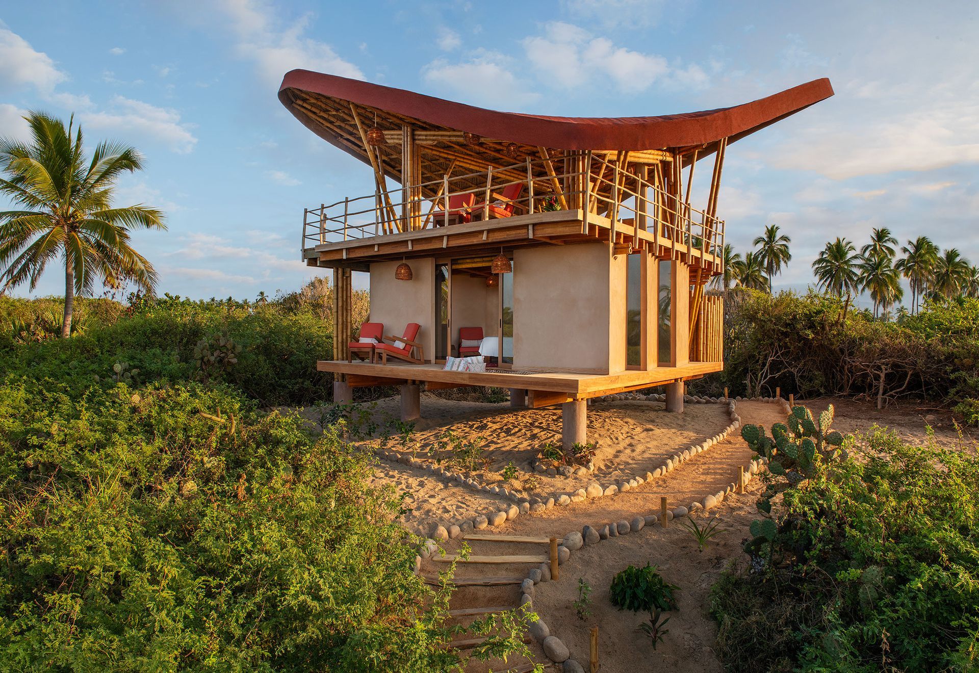 A small house with a red roof is surrounded by trees.