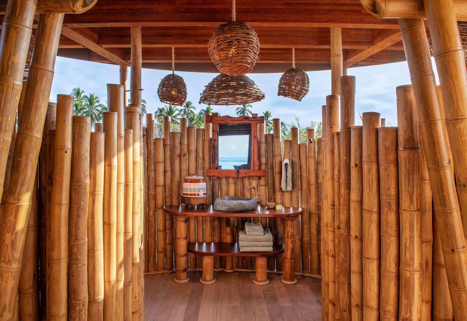 A bathroom with a sink and a mirror surrounded by bamboo sticks.