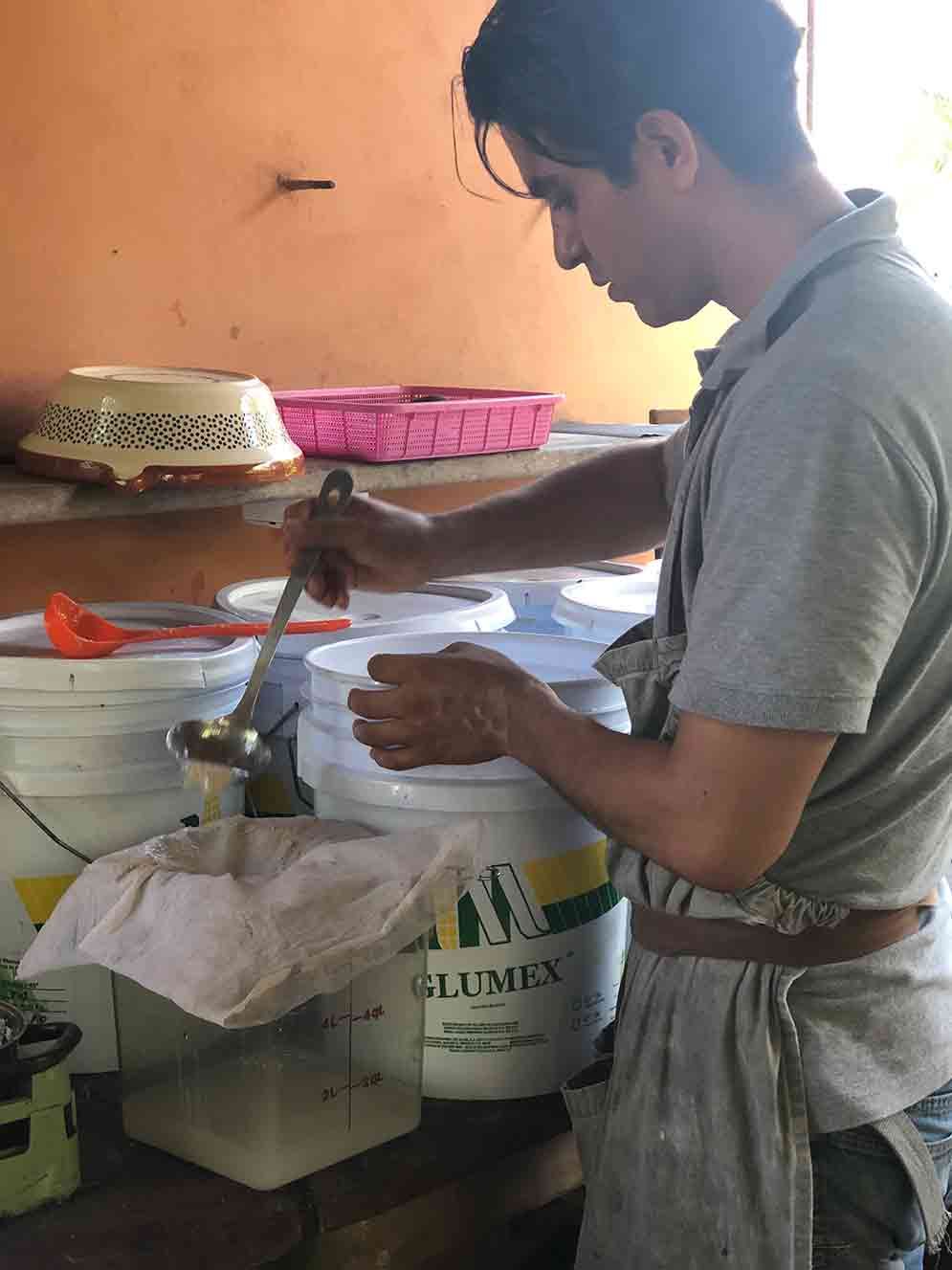 A man is mixing something in a bucket with a spoon.