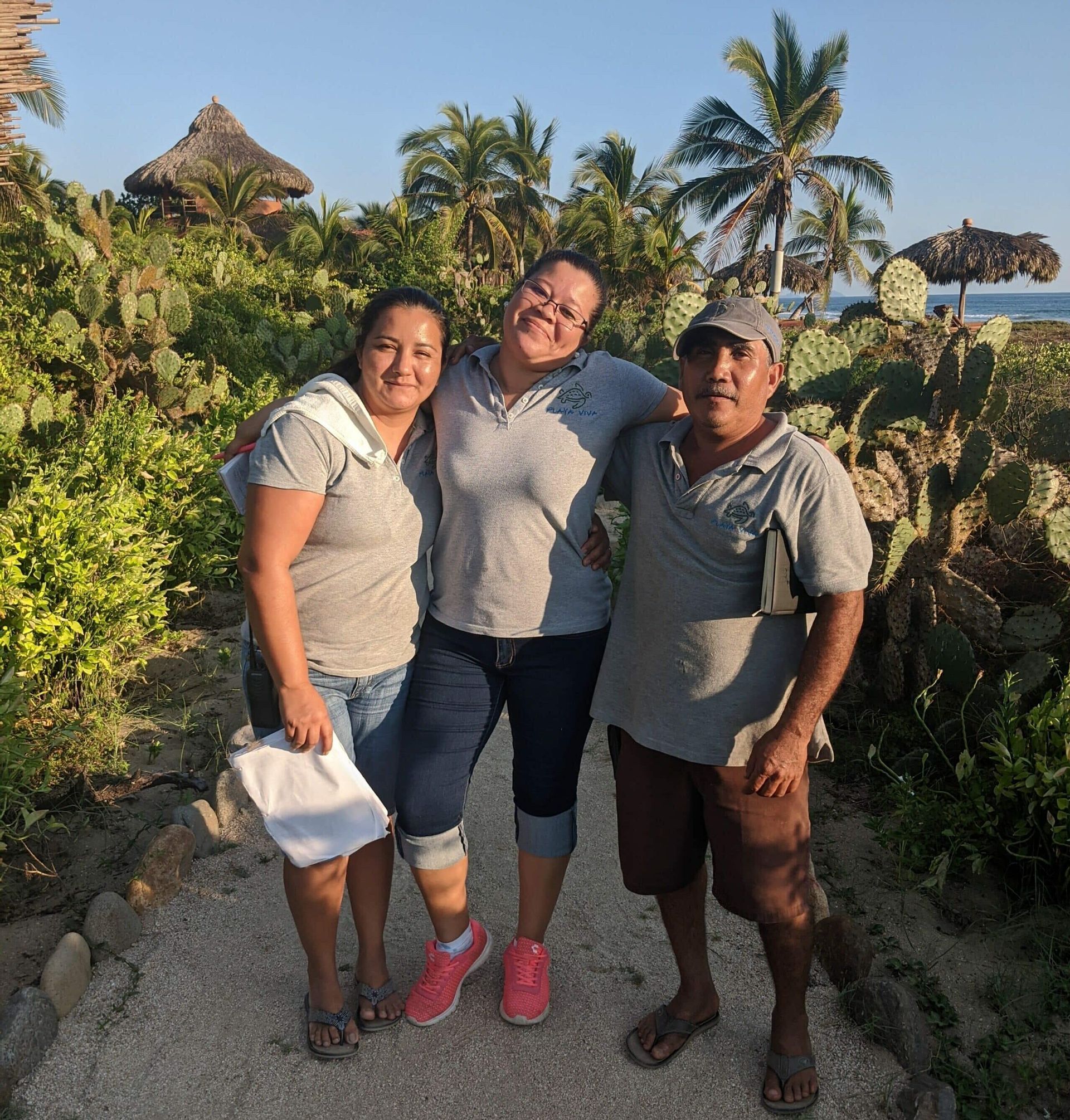 Three people posing for a picture in front of palm trees