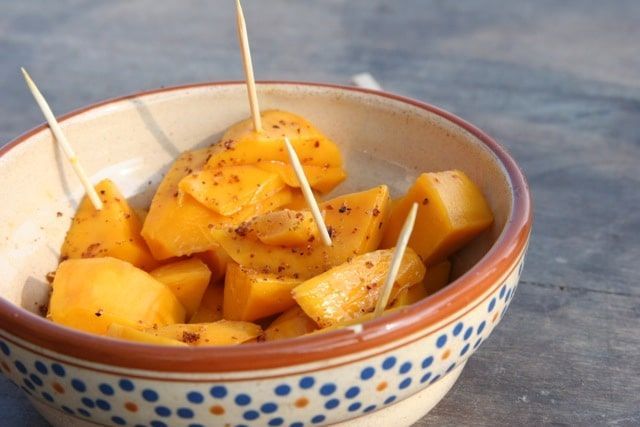 A bowl of fruit with toothpicks in it on a table.