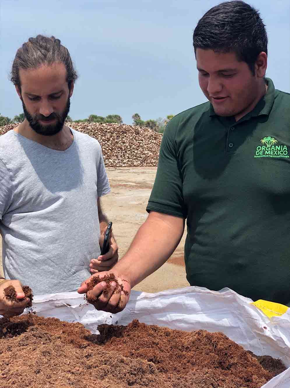 Two men are standing next to each other looking at a pile of dirt.