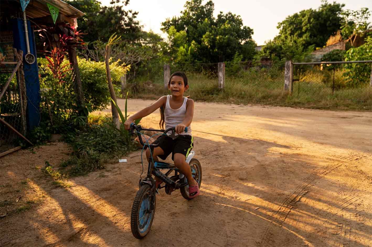 A young boy is riding a bike on a dirt road.