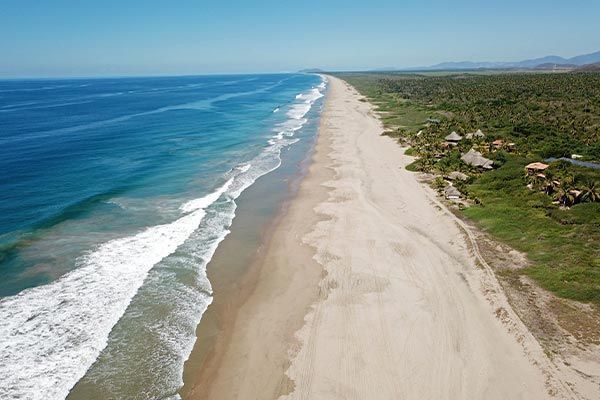 An aerial view of a long sandy beach next to the ocean.