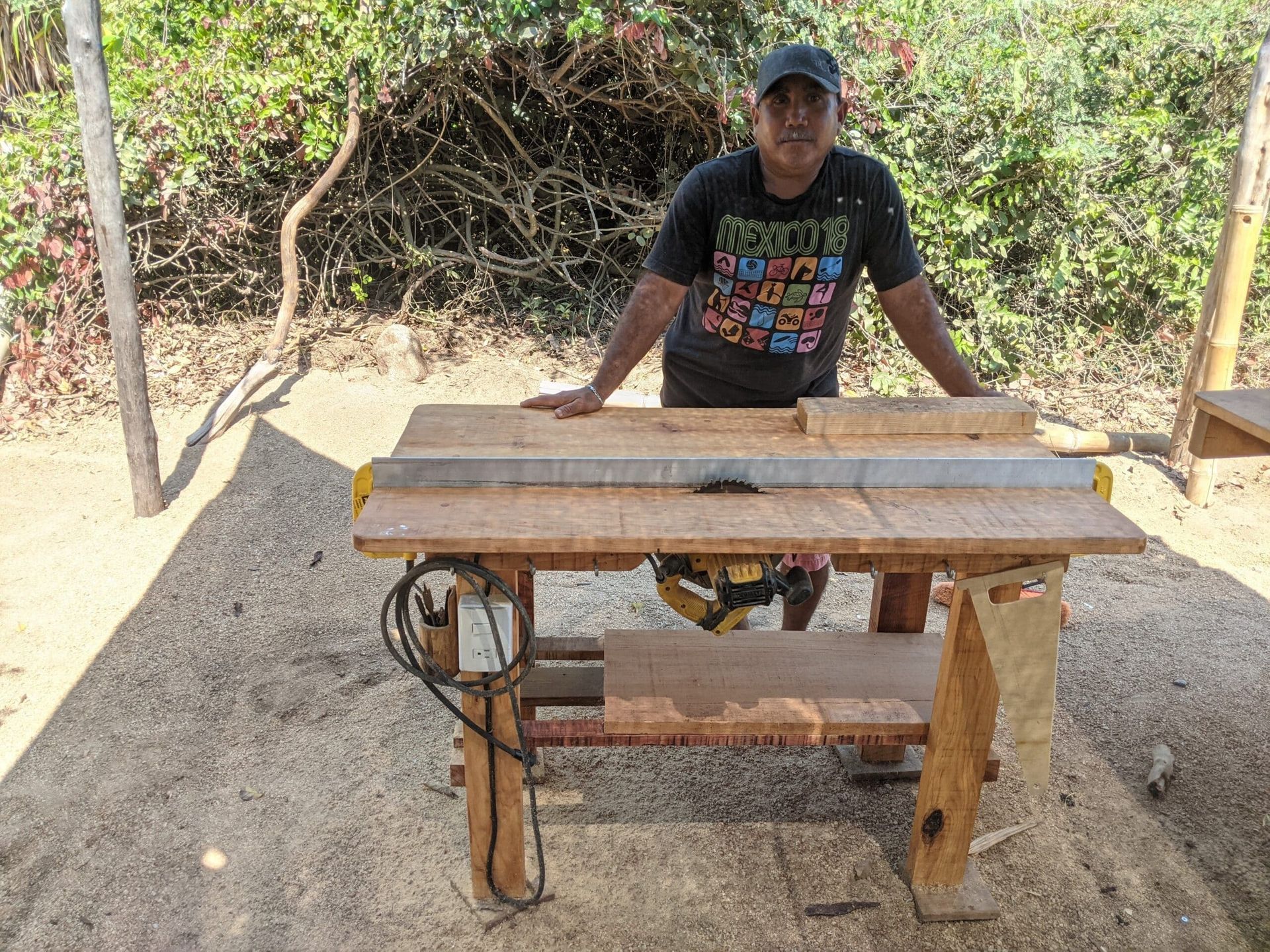 A man is standing next to a wooden table with a saw on it.