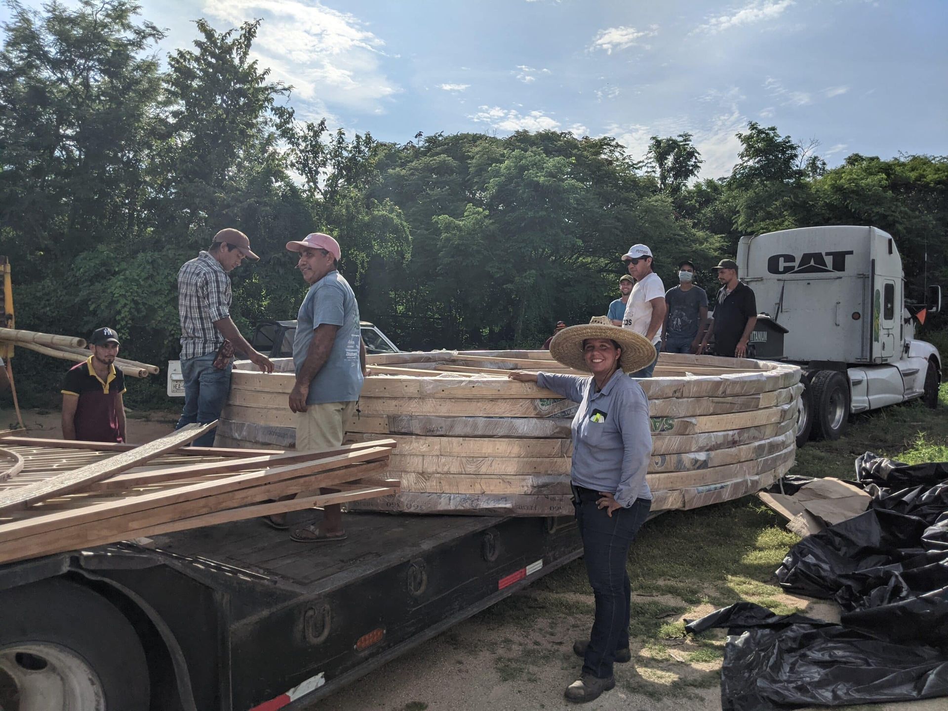 A group of people are standing in front of a cat semi truck.