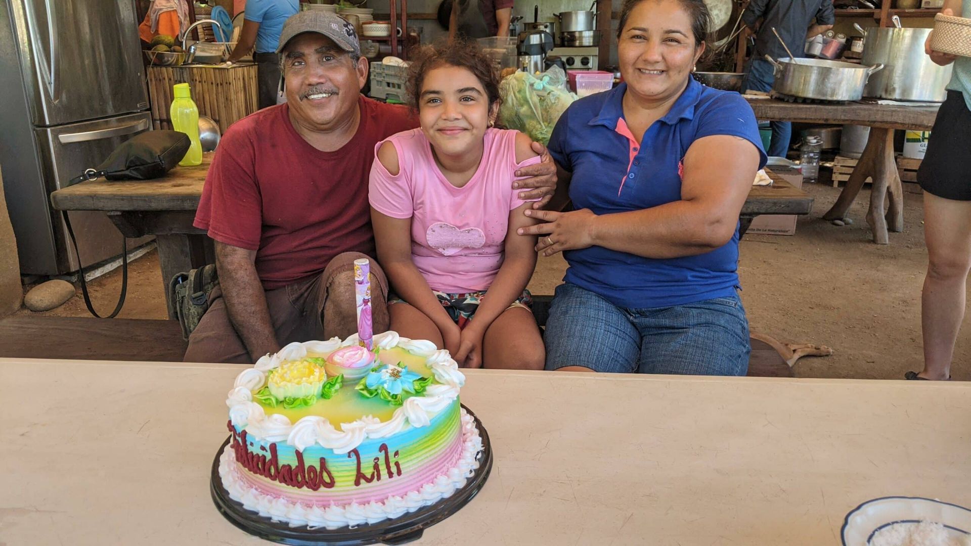 A family is sitting at a table with a birthday cake.