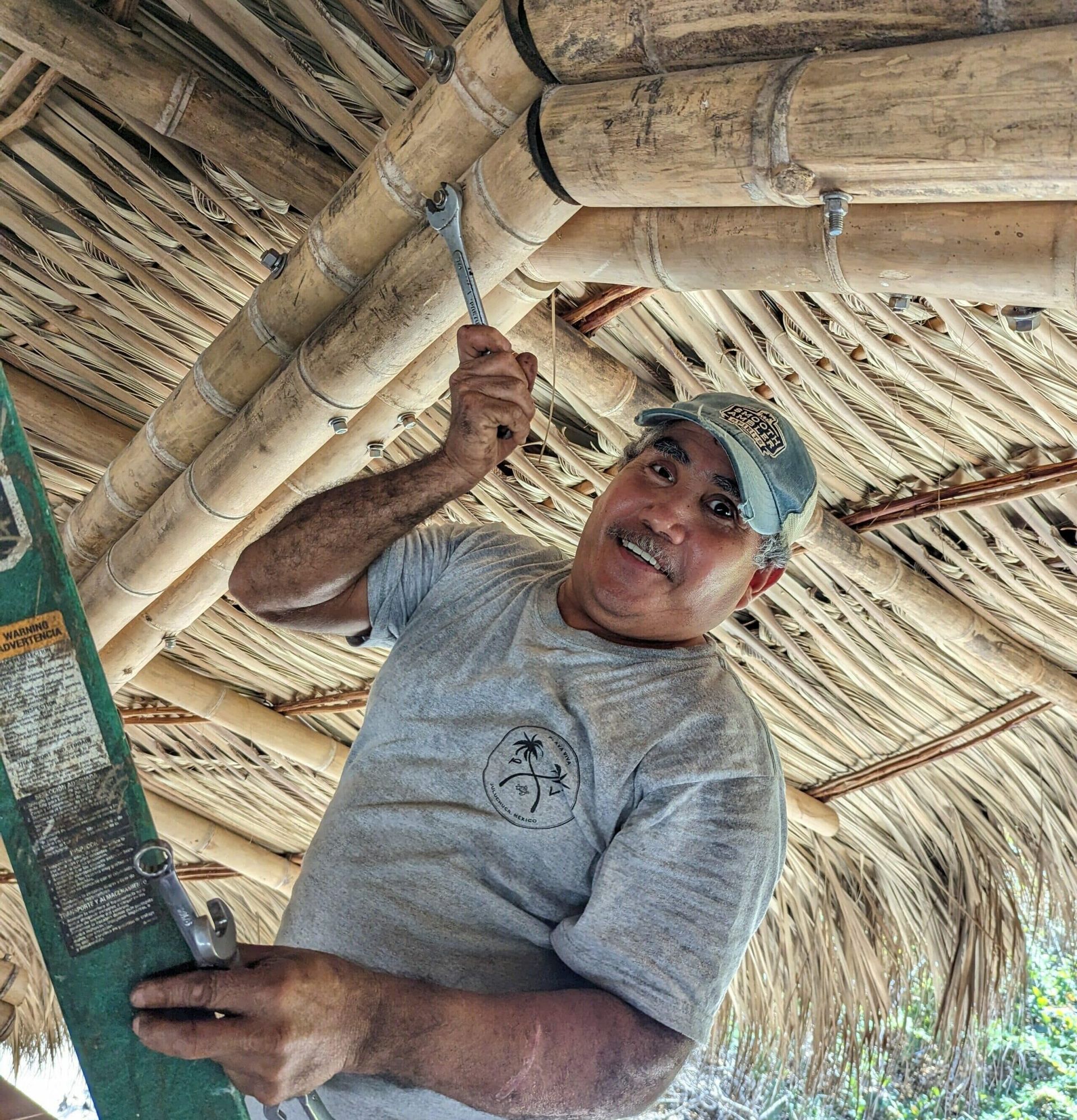 A man is holding a ladder under a thatched roof