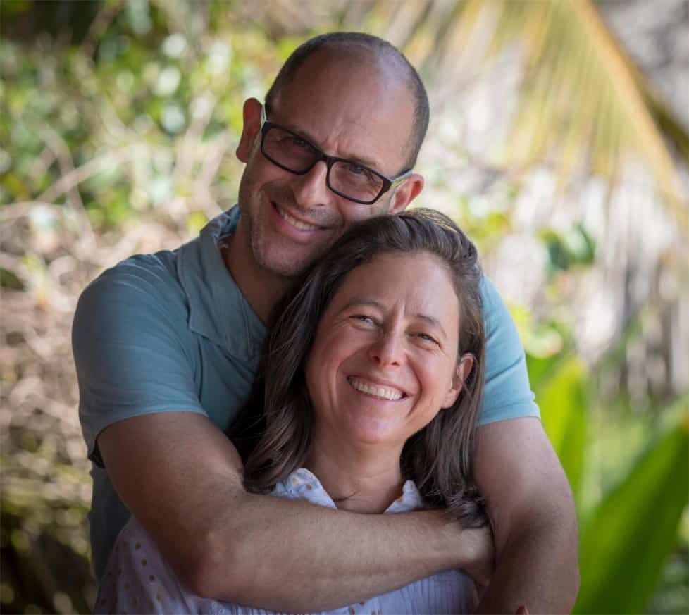 A man and a woman are hugging each other and smiling for the camera.
