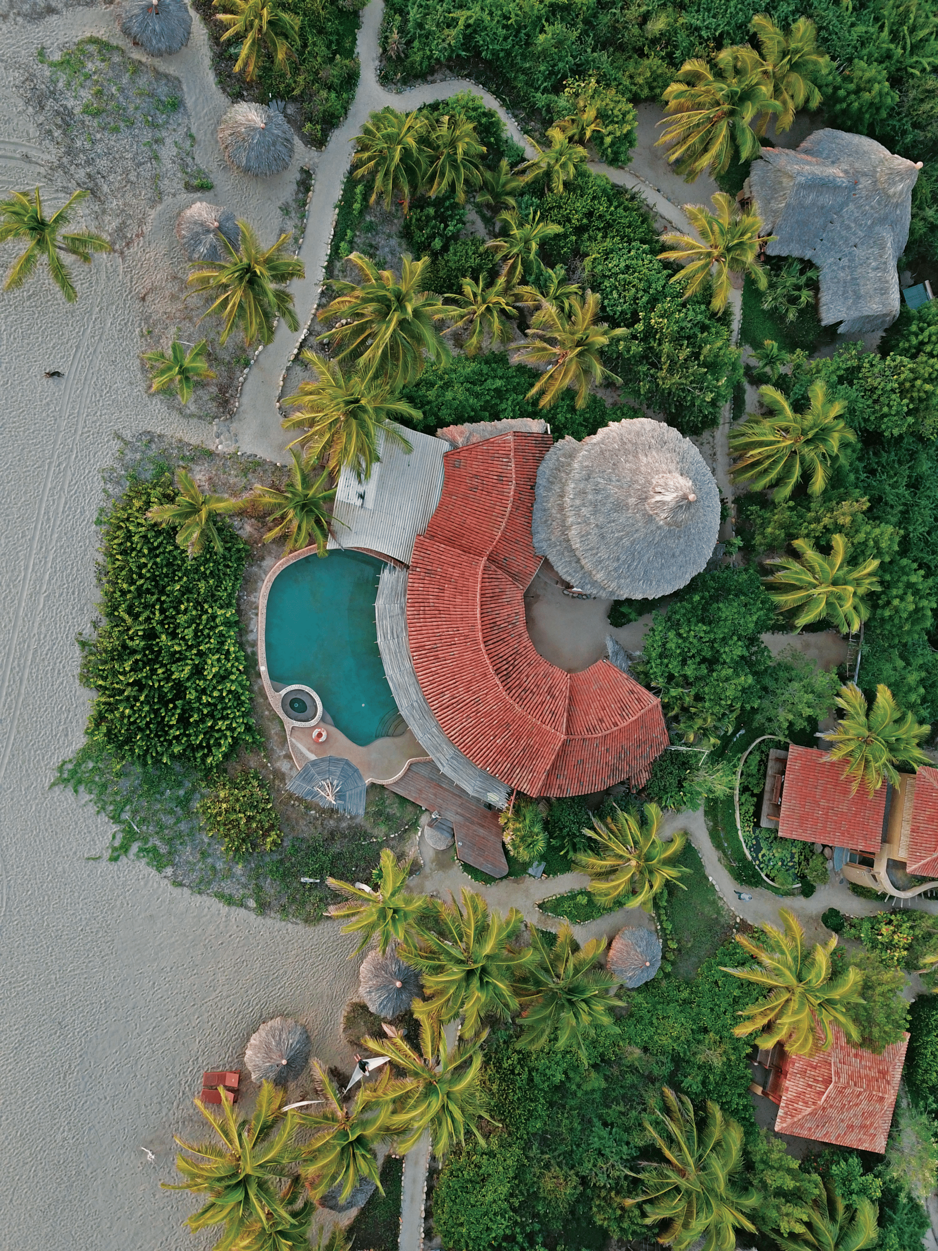 An aerial view of a tropical resort with a pool and palm trees.