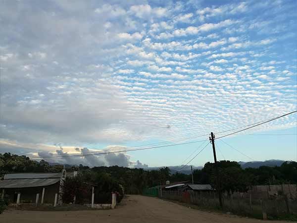 A dirt road with a cloudy sky in the background