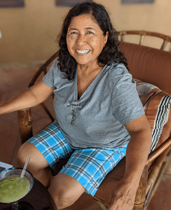 A woman is sitting in a chair with a drink in her hand.