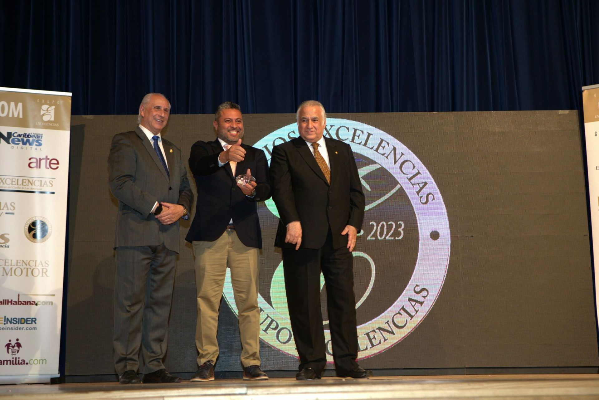 Three men in suits and ties are standing on a stage.