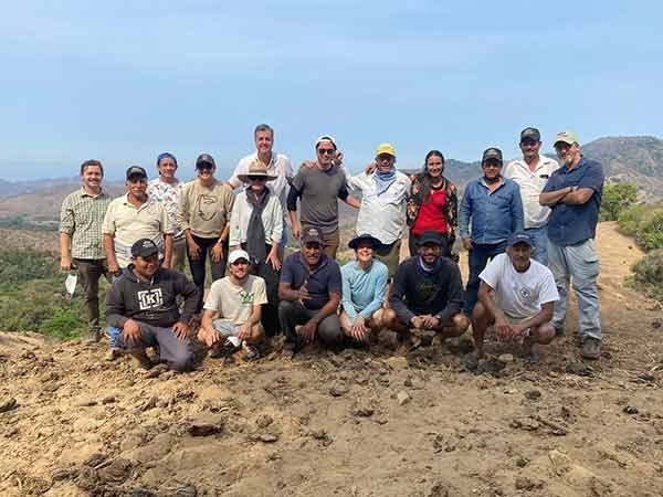 A group of people are posing for a picture on top of a dirt hill.