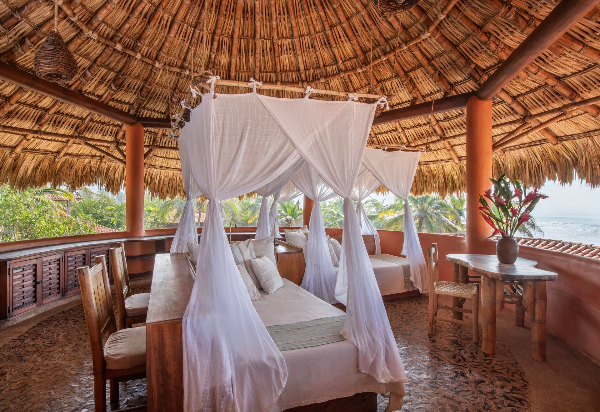 A canopy bed in a room with a thatched roof
