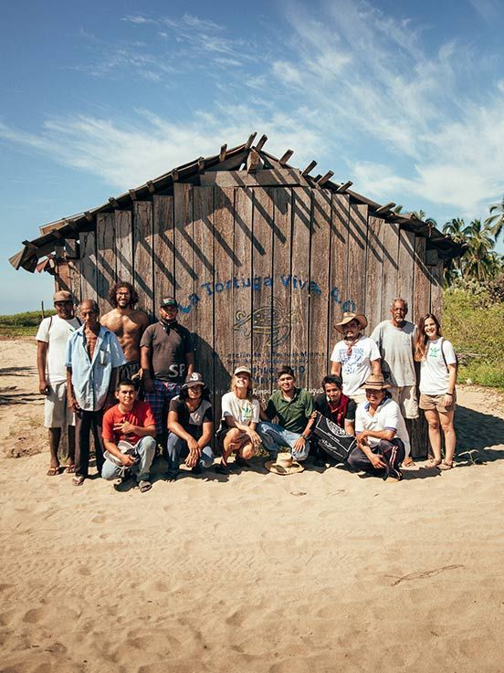 A group of people are posing for a picture in front of a wooden building.