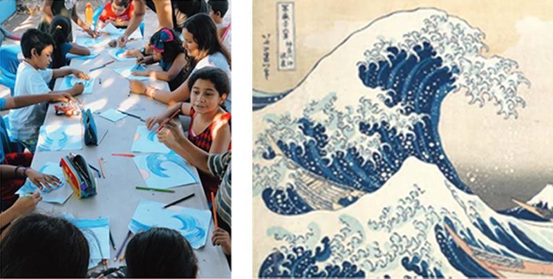 A group of children are sitting at a table with a picture of a wave behind them