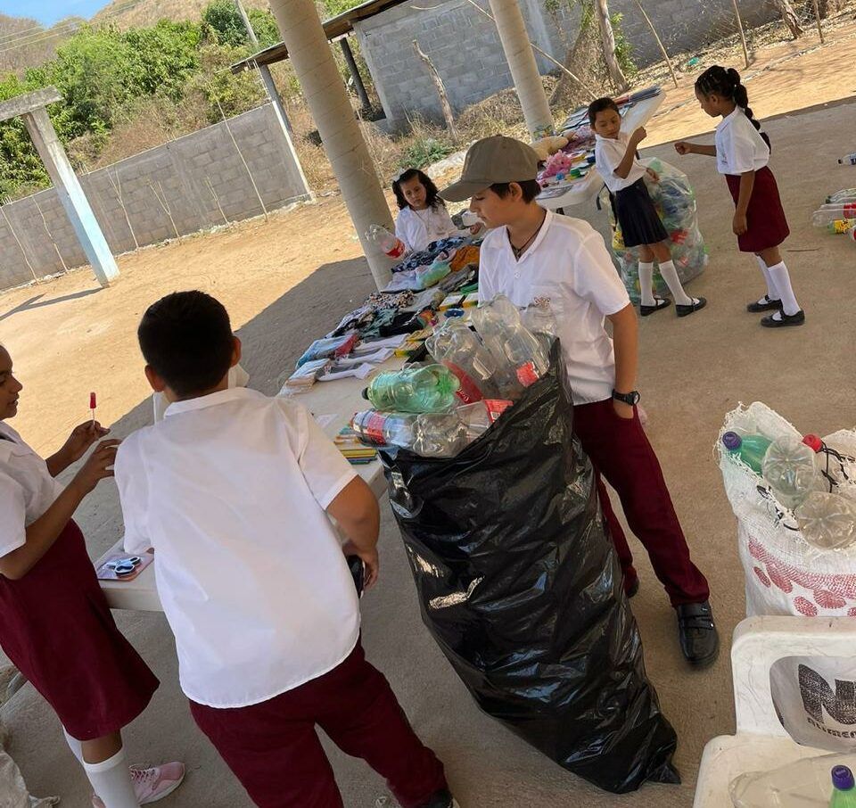 A group of children are standing around a table full of plastic bottles