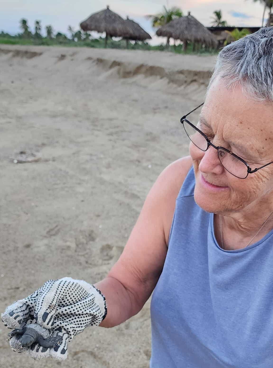 A woman wearing glasses is holding a small object in her hand