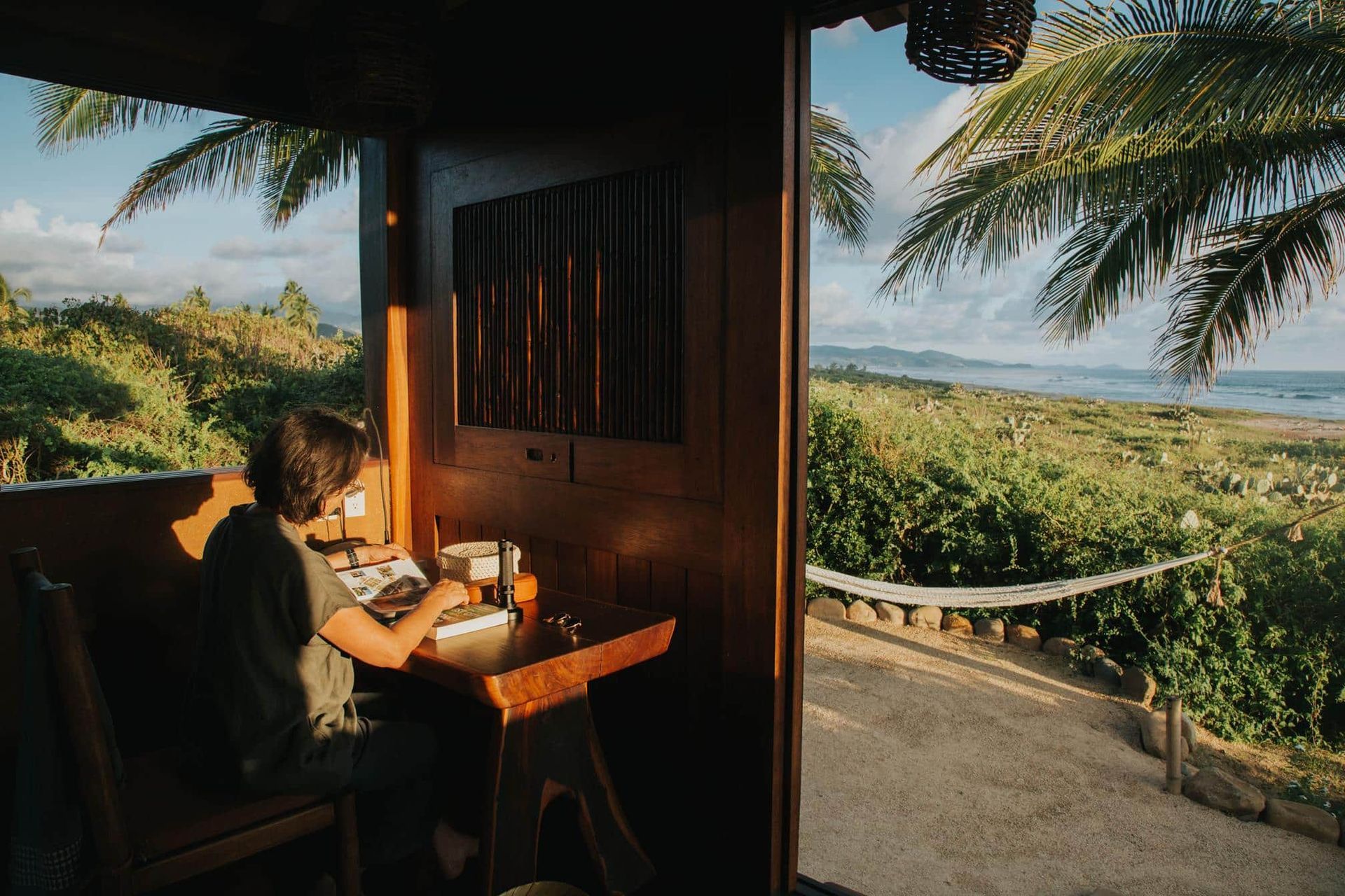 A man is sitting at a table in a cabin with a view of the ocean.