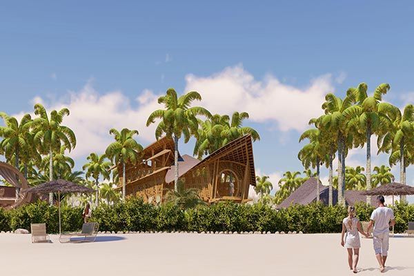 A man and a woman are walking on a beach in front of a wooden house.