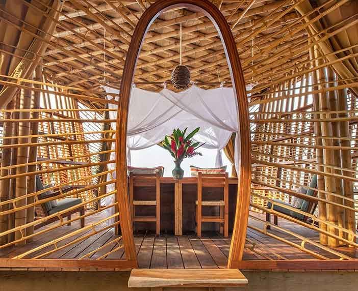 A wooden hut with a bed and chairs inside of it.