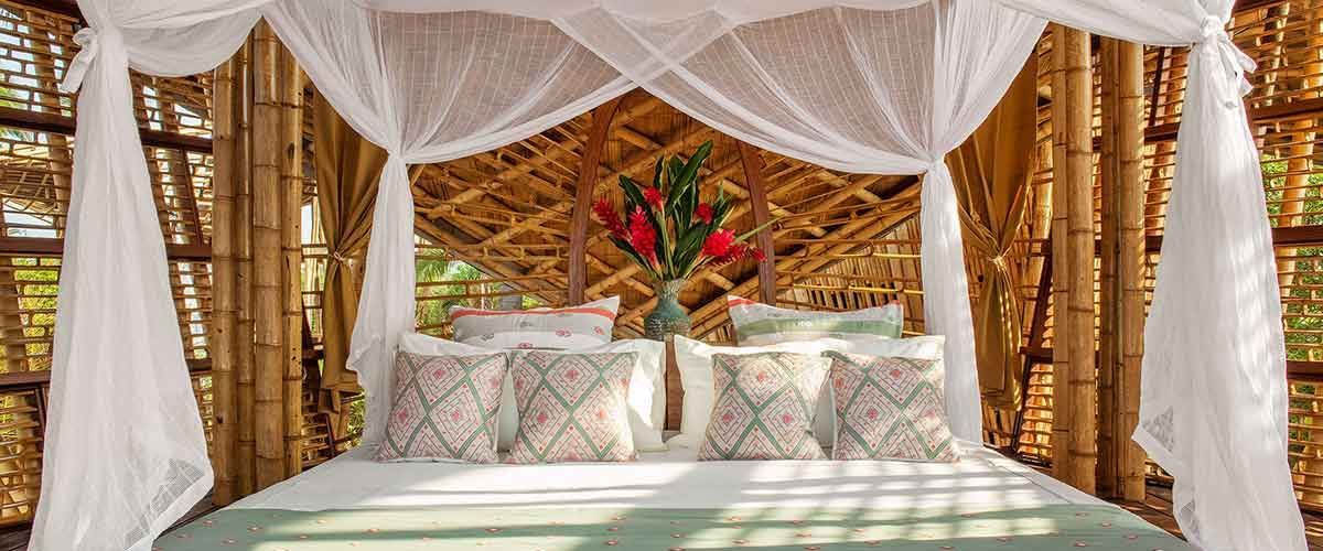 A bed with a canopy and pillows in a bamboo room.
