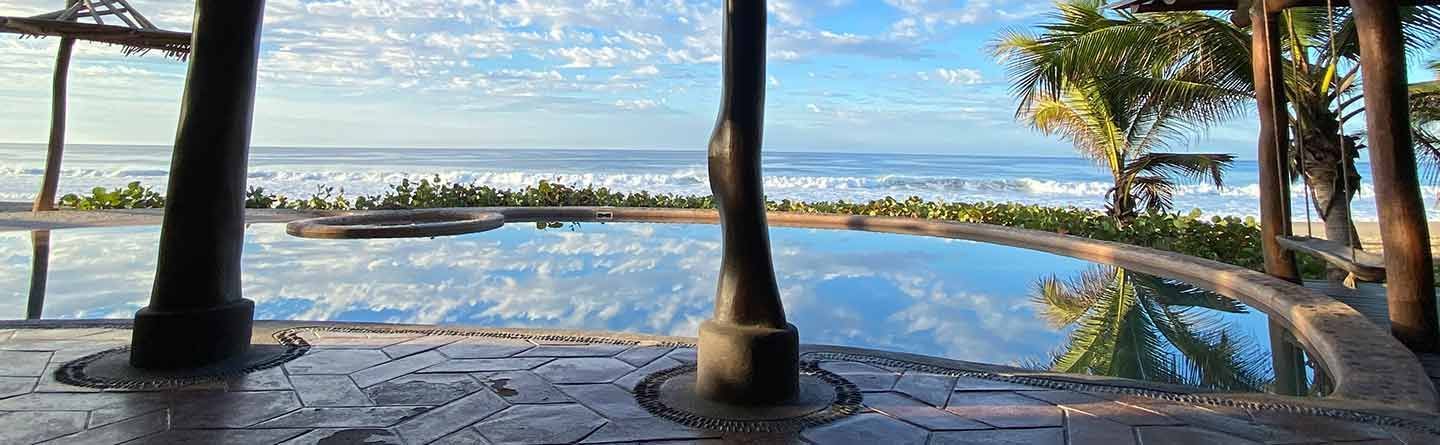 There is a swimming pool with a view of the ocean.