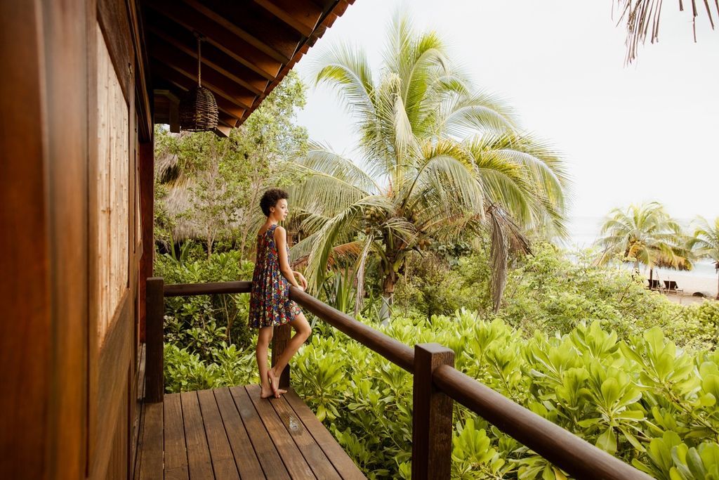 A woman is standing on a balcony overlooking a lush green forest.