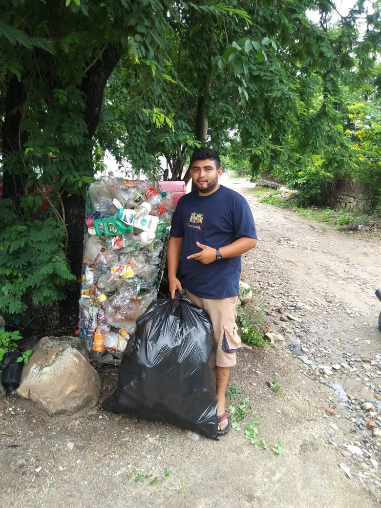 A man is standing next to a pile of plastic bottles.