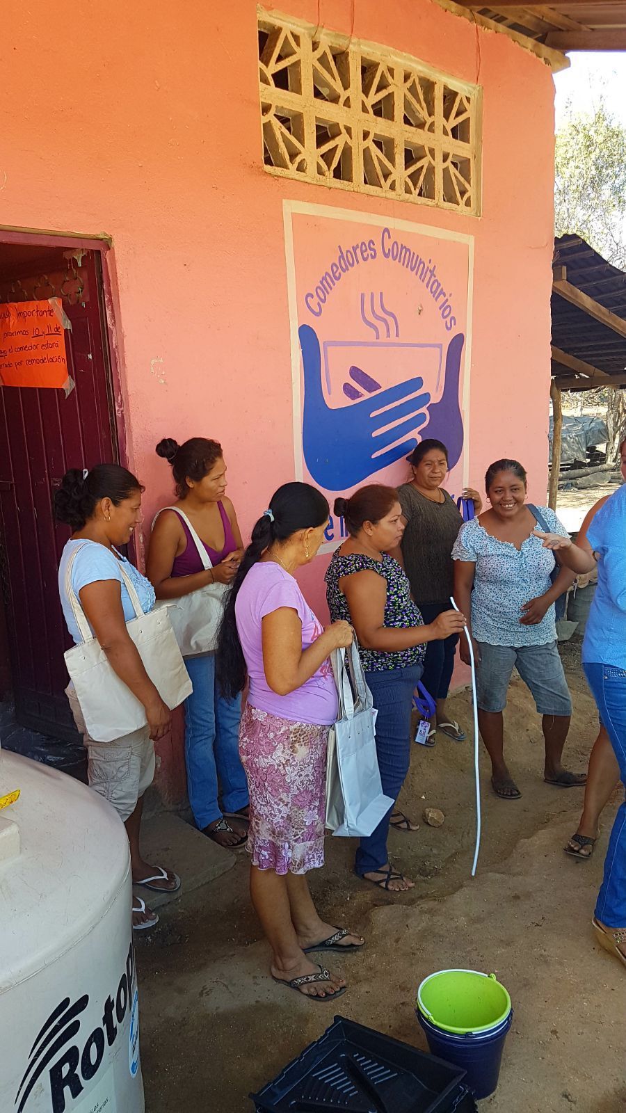 A group of women are standing in front of a pink building.