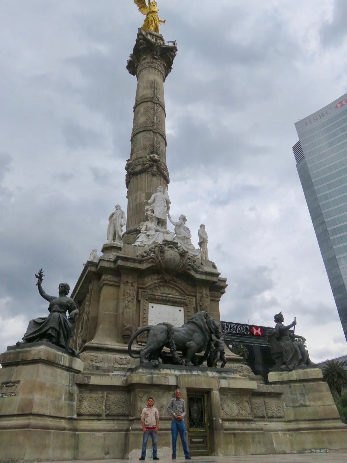 Two men are standing in front of a large statue of a bull.