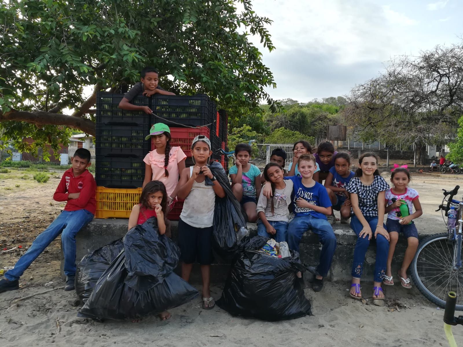 A group of children are posing for a picture with trash bags.