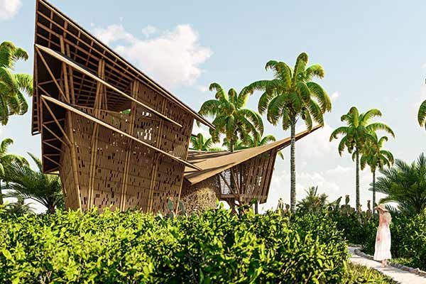 A woman in a white dress is standing in front of a wooden building surrounded by palm trees.