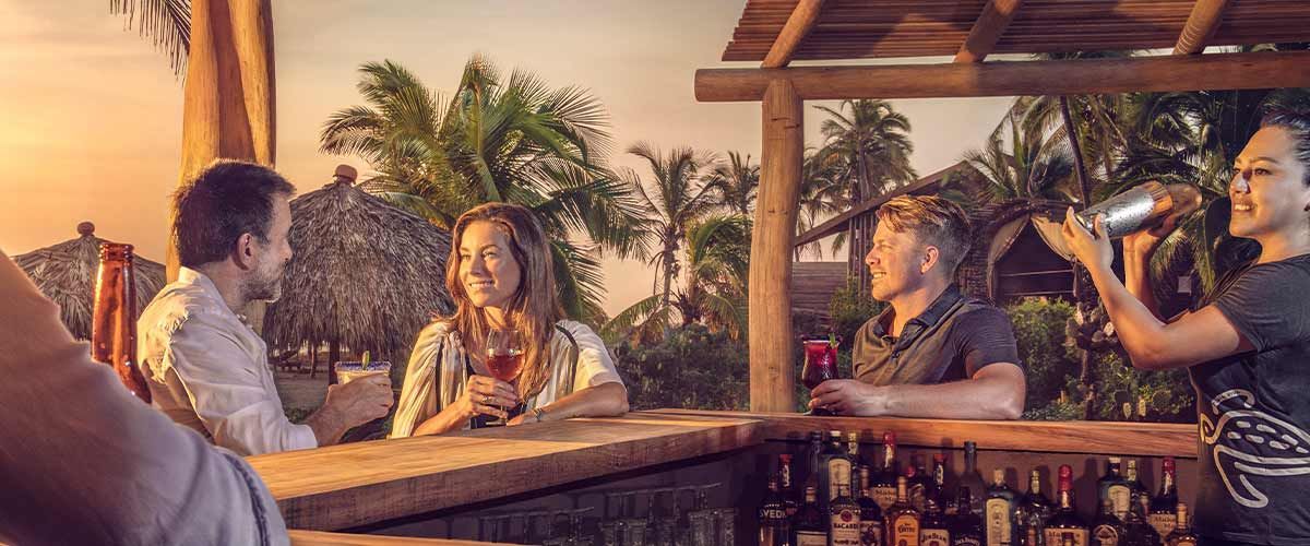 A group of people are sitting at a bar drinking beer.