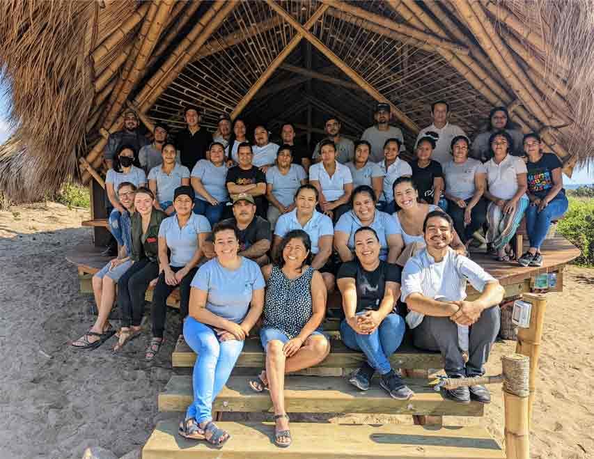A group of people are posing for a picture in front of a hut.