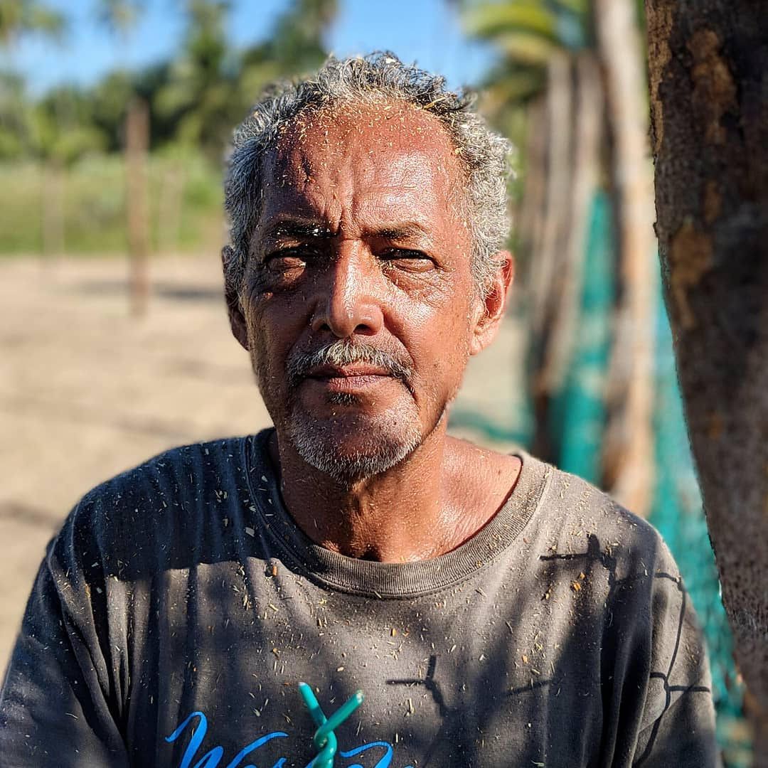 A man with a beard is wearing a gray shirt with the word wax on it