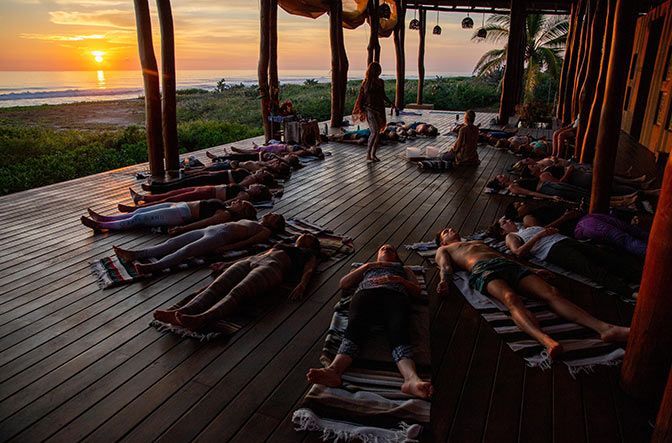 A group of people are laying on a wooden deck at sunset.